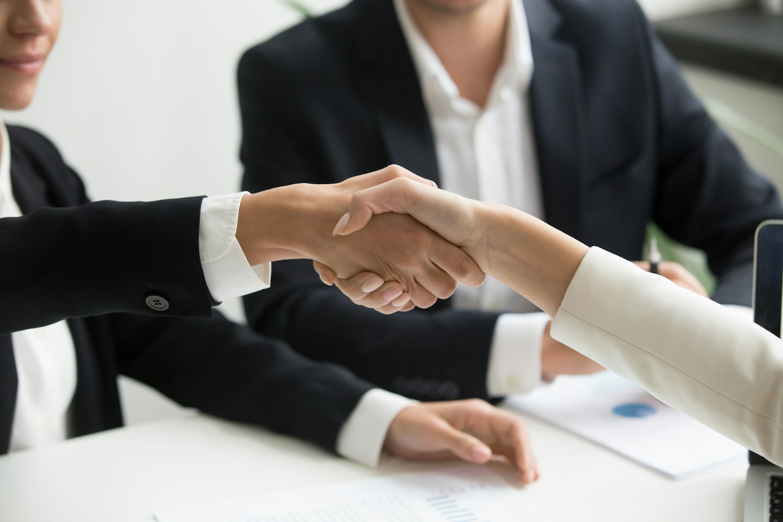 Two professionals shaking hands over an agreement, choosing a VAPT provider