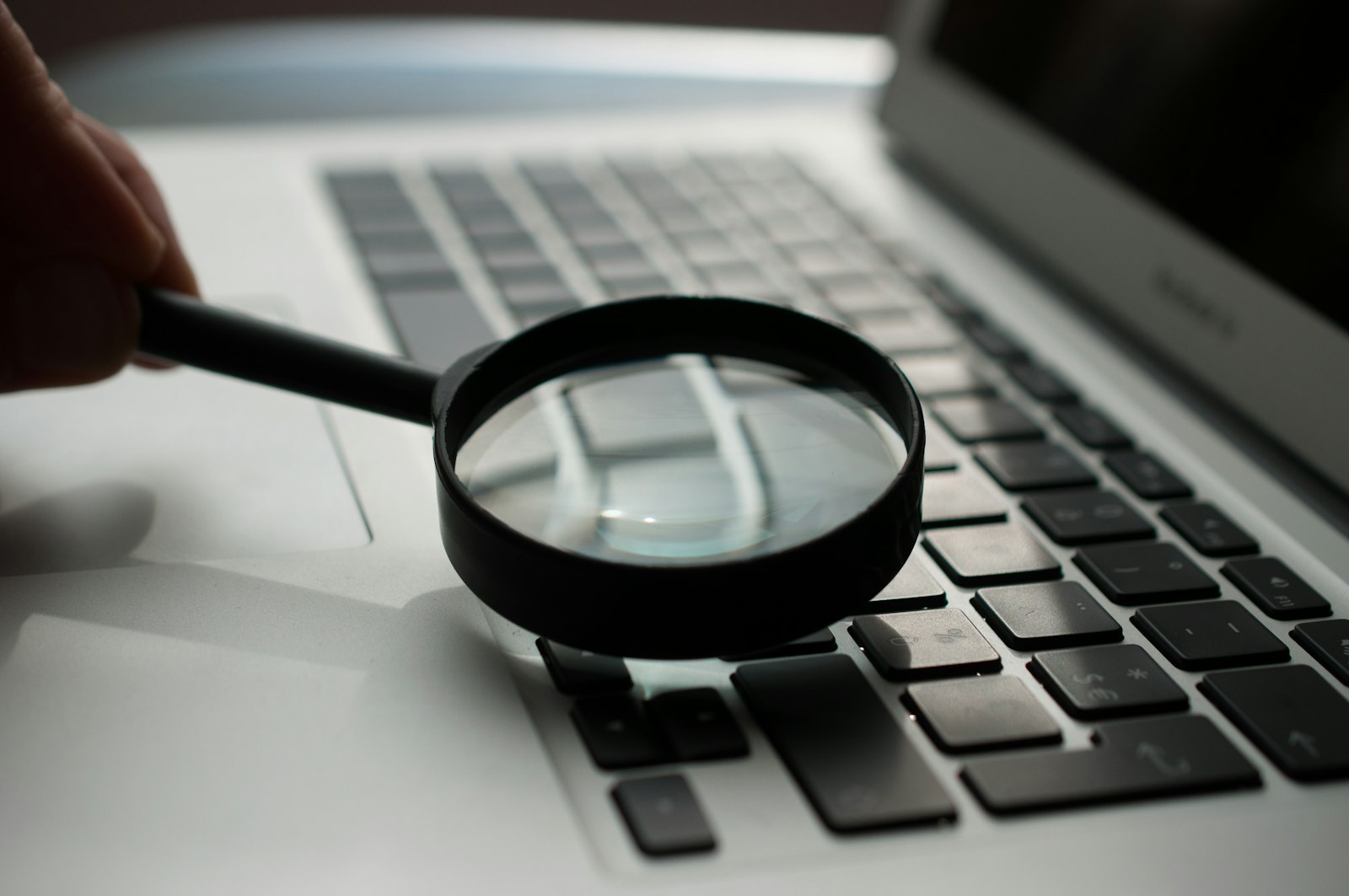 Magnifying glass over source code, representing manual penetration testing findings verified with proof of exploit